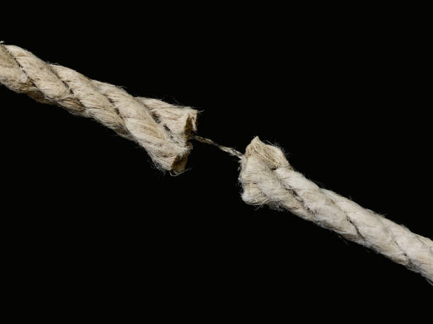 istock The torn rope is about to break, a black background. The rope is held on one thread. Concept: life in the balance. 1205757568