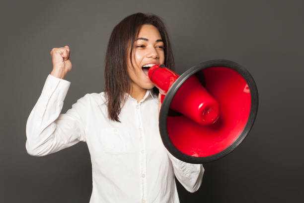 istock Black woman with red loudspeaker on gray background 1205759575