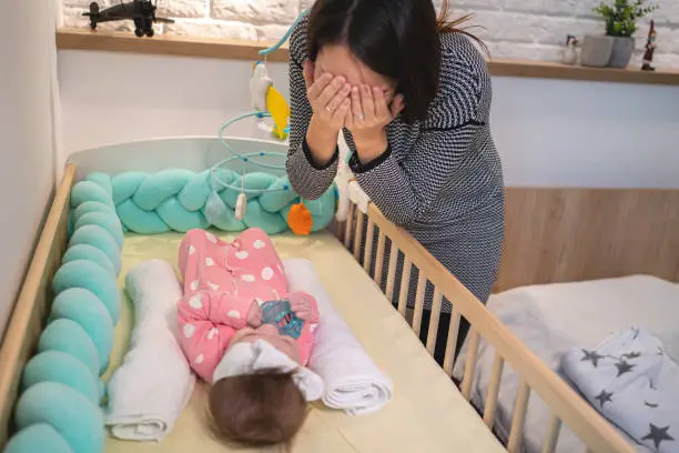Single mother japanese ethnicity, playing with her baby girl in nursery room