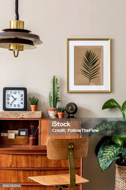 Stylish Retro Composition Of Home Office Interior With Vintage Wooden Cabinet Chair Plants Clock Pendant Lamp And Elegant Accessories Gold Mock Up Poster Frame Retro Home Decor Template Stock Photo - Download Image Now
