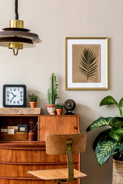 стильная ретро композиция интерьера домашнего офиса с винтажным деревянным шкафом, стулом, растениями, часами, подвесной лампой и элегантн - в помещении фотографии стоковые фото и изображения