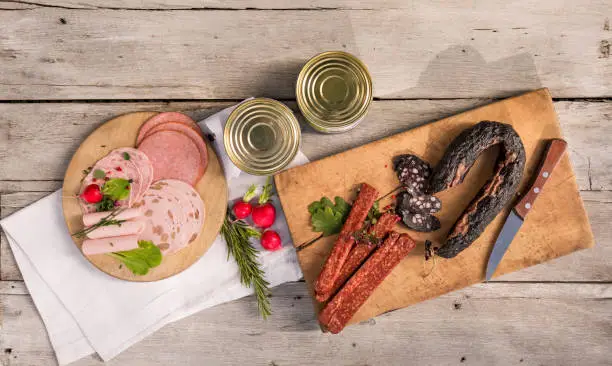 Composition with Landjäger, black sausage, salami, ham, Lyoner and canned sausage decorated with radishes and herbs