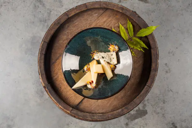 Various cheeses decoratively arranged on an old wooden barrel