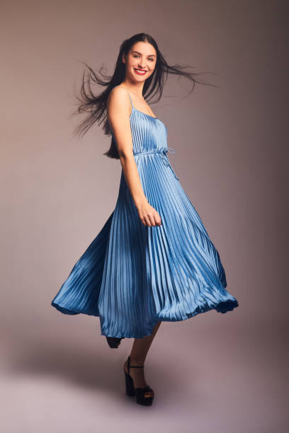 istock Smiling young brunette woman dancing in a blue dress 1205763529