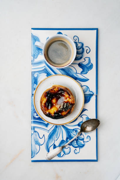 Pastel de nata. Traditional Portuguese dessert, egg tart and cup of coffee on Traditional Azulejo tiles over marble background. Top view stock photo
