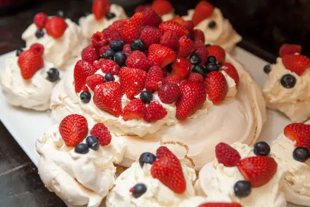 A dessert of strawberry, raspberry and blueberry on a meringue nest filled with whipped cream