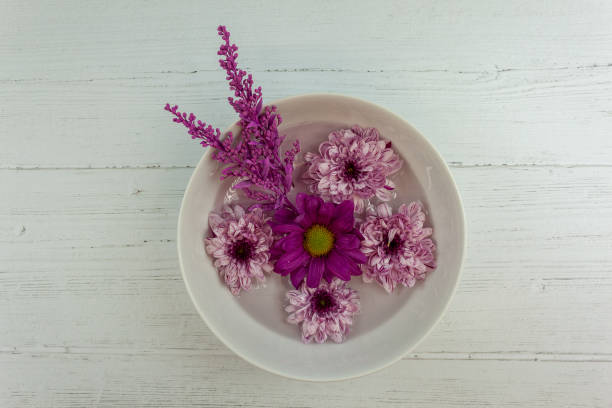 istock Flowers float on water inside a dish. The dish sits on a silver wooden background 1205765887