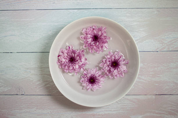 istock Flowers float on water inside a dish. The dish sits on a silver wooden background 1205766499