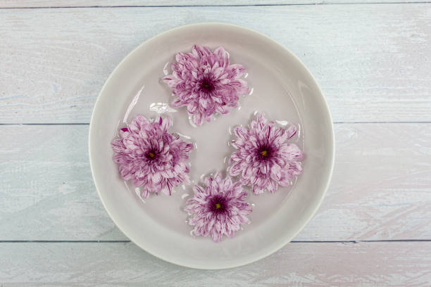 istock Flowers float on water inside a dish. The dish sits on a silver wooden background 1205766615