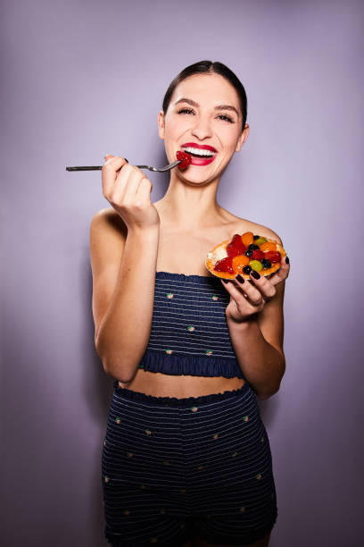 istock Young woman laughing and eating a fruit tart with a fork 1205766961