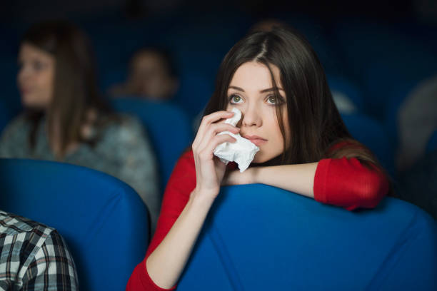 Sympathizing With Characters Beautiful, sad woman watching the movie at the cinema and crying wiping tears stock pictures, royalty-free photos & images