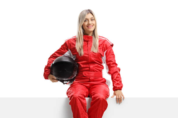 istock Female racer in a suit holding a helmet and sitting on a panel 1205771275