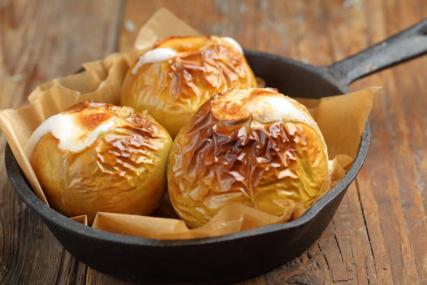 pommes cuites au four dans une casserole en fer sur une table rustique - baked apple food meal dessert photos et images de collection