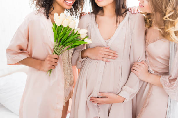 vue recadrée de jeune femme enceinte avec des amies et des fleurs de tulipe sur la douche de chéri - human pregnancy baby shower image color image photos et images de collection