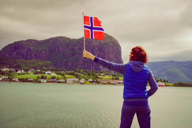 istock Tourist with norwegian flag on fjord 1205779014