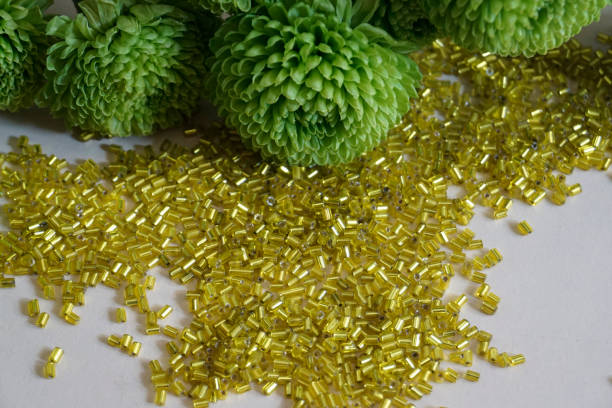 cuentas de toho tubular amarillo y crisantemo verde sobre fondo crema claro. - glass jewelry bead bugle fotografías e imágenes de stock