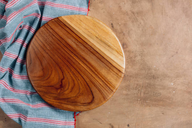 istock Wooden cutting board over towelon beige rustic kitchen table. Space for your recipe or menu. Top view. 1205781983