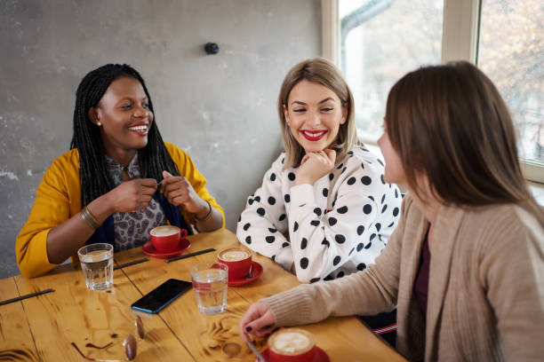 istock Beautiful young women multi-ethnic drinking coffee and talking in cafe 1205782028