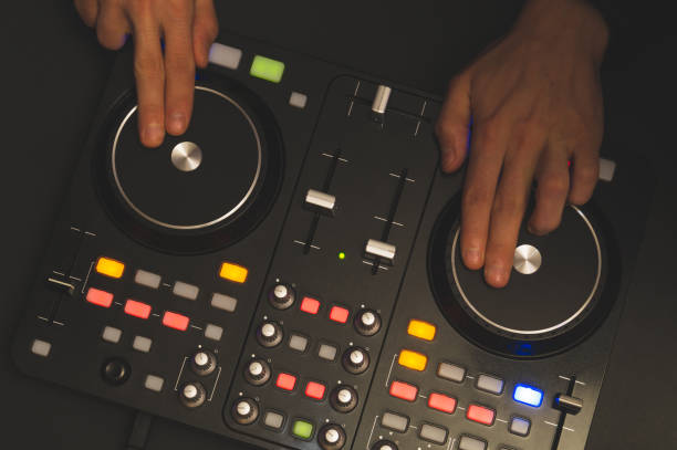 istock DJ plays music. sound mixer controller with knobs and sliders. hands on the mixing deck and turntables at dark with illuminated controls 1205782327