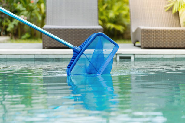 Cleaning swimming pool of fallen leaves with skimmer net equipment Cleaning swimming pool of fallen leaves with skimmer net equipment against sun resort loungers at sunny summer day fishing net photos stock pictures, royalty-free photos & images