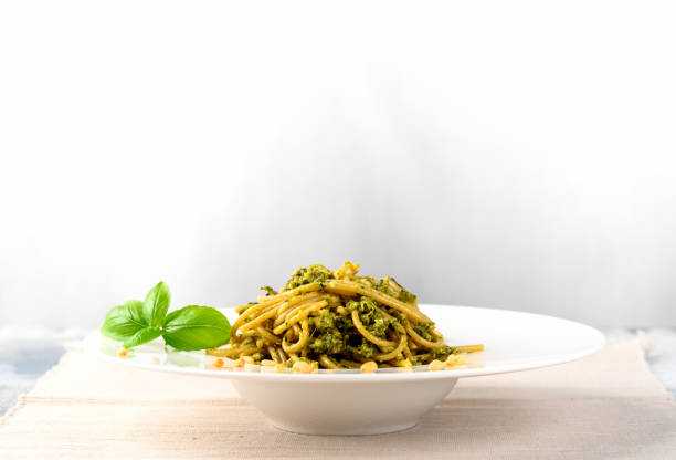 istock Plate of pasta with pesto sauce on light background. 1205783846