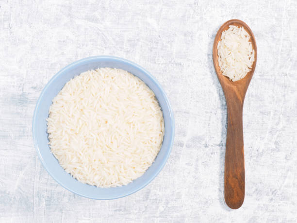 istock Indian long grain Basmati rice in blue ceramic bowl and spoon on white concrete background 1205784883