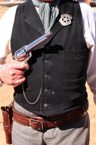 Close up of a US Marshal tin star pinned to a black vest worn by a re-enactor at the Cavalry day event Fort Lowell, Tucson AZ