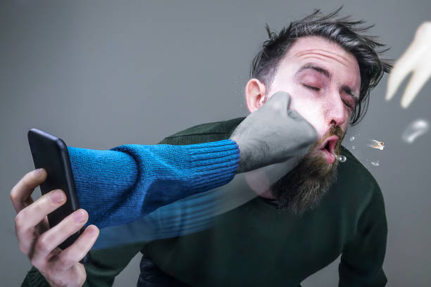 homme au téléphone avec un bras sortant du téléphone et le frappant au visage - punching one person shaking fist fist photos et images de collection