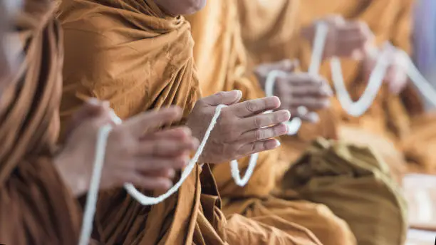 Photo of Buddhist monk praying hands in buddhism tradition ceremony.