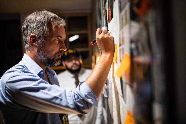 istock FBI detective standing in front of wall with map on it and writing a new lead on a case 1205789317