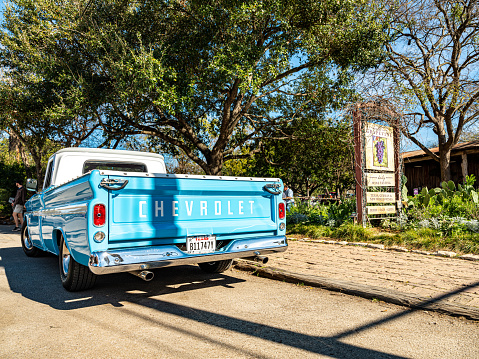 Gruene, Texas, USA- February 2, 20202. Center of a small town og Gruene in suburbs of San Antonio, Texas. Originally established by German emigrants, now a vibrant community of many different nationalities and backgrounds. Baby blue vintage Chevrolet pick up truck parked on the side of the road, near main town intersection. Restaurant venue in the background.