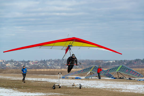 Hang glider start at the airfield. One bright hang glider in the air other pilots are ready to take off 2020-02-09 Byshiv, Ukraine. Hang glider start at the airfield. One bright hang glider in the air other pilots are ready to take off para ascending stock pictures, royalty-free photos & images