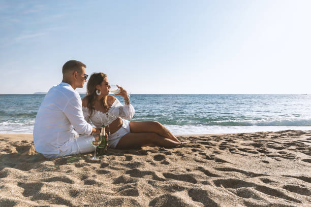 istock Happy couple seating with champagne on the beach. Summer vacations concept. 1205792405