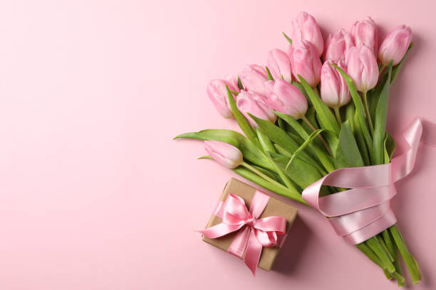 istock Bouquet of tulips and gift box on pink background, space for text 1205793465
