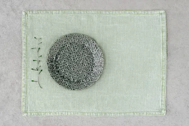 Green ceramic plate with floral design on linen placemat.