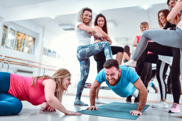 maschio che fa f spintoni mentre le femmine lo bullizzano in palestra - yoga men male gymnastics foto e immagini stock