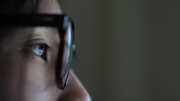 Woman watching screen, reflection in glasses