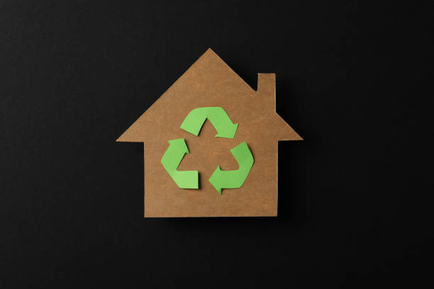 istock Cardboard house with recycling sign on black background, space for text 1205801464