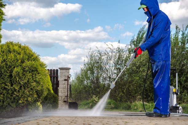 Driveway Pressure Washing Men in Blue Rain Coat Cleaning His Driveway Using Pressure Washer. power in nature stock pictures, royalty-free photos & images