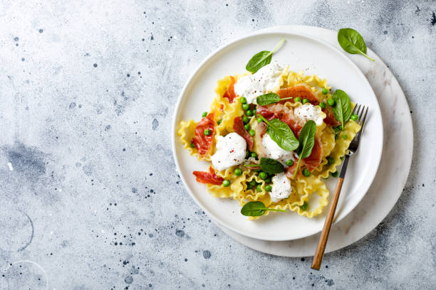 Italian pasta mafalde with green peas, prosciutto, burrata,  and spinach