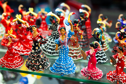 Ceramic mosaic and painted flamenco dancers figurines in colorful traditional dresses on showcase of Spanish souvenir shop