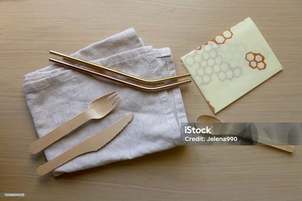 Zero Waste Kit Linen cloth, reusable straws, wooden cutlery and beeswax wrap on a wooden table. Set of zero waste kitchen products. Top view. Beeswax Wrap Stock Photo