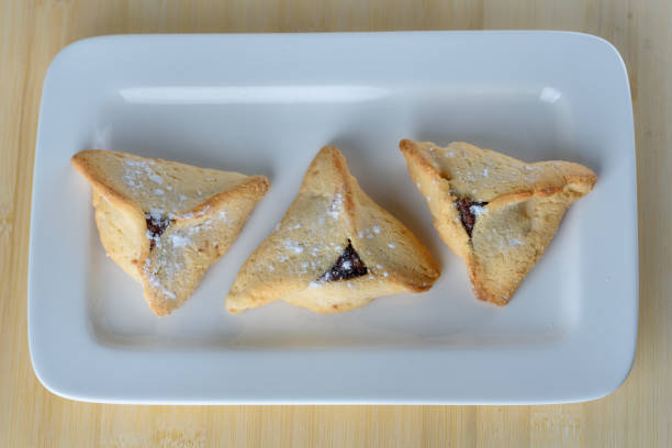 istock Purim holiday celebration. Hamantaschen cookies on white dish. Overhead view 1205804529