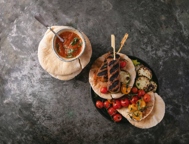 Traditional turkish Grilled Lula Kebabs served with vegetables, pita bread and home made tomato sauce over a rustic metal background. Top View. stock photo