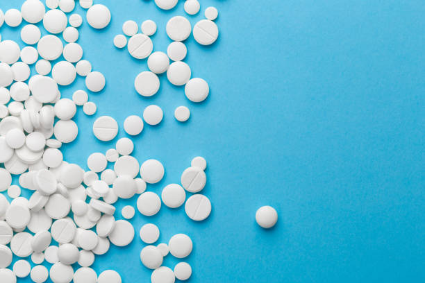 istock scattered white pills on a blue table. Layout for special offers such as advertising or other ideas. The concept of medicine, pharmacy and healthcare. Space for copy. 1205805471
