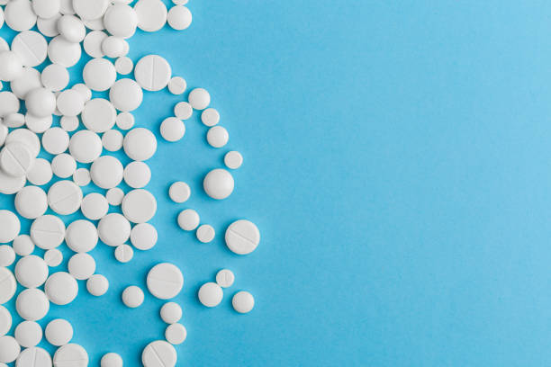 istock scattered white pills on a blue table. Layout for special offers such as advertising or other ideas. The concept of medicine, pharmacy and healthcare. Space for copy. 1205805538