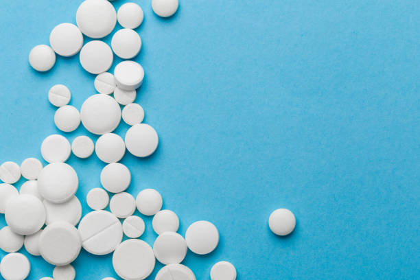 istock scattered white pills on a blue table. Layout for special offers such as advertising or other ideas. The concept of medicine, pharmacy and healthcare. Space for copy. 1205805686
