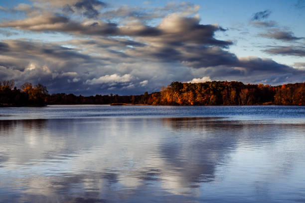 Reflection of Fall Colored Trees with a Cloudy Sky over Sand Lake in Hillsdale, MI, United States