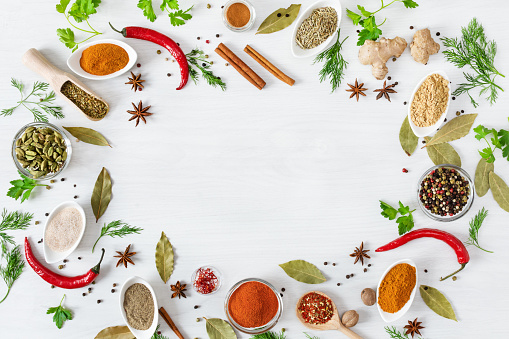 Various assorted colorful spices and herbs on white wooden background top view. Flat lay. Copy space.