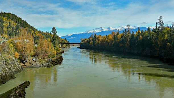 istock River, bridge and forests with snow capped mountains 1205807802